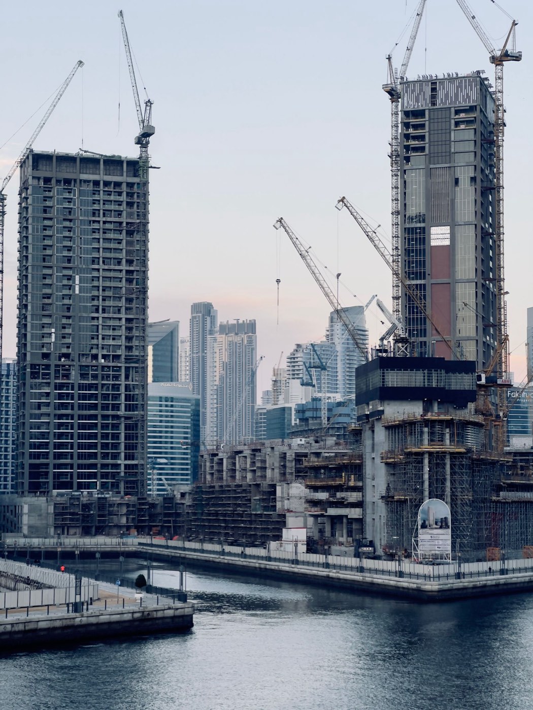 Residential towers under construction with tower cranes by the water